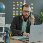 Small business owner working at a laptop and reviewing business paperwork