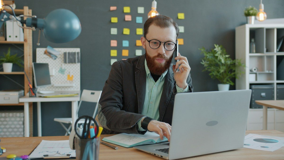 Small business owner working at a laptop and reviewing business paperwork